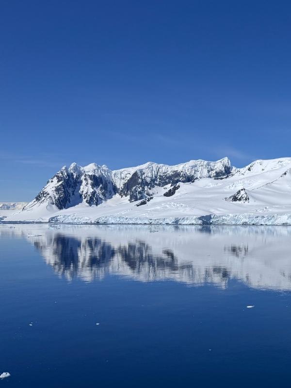 Pristine early-season Antarctic mountains mirrored in glassy calm water