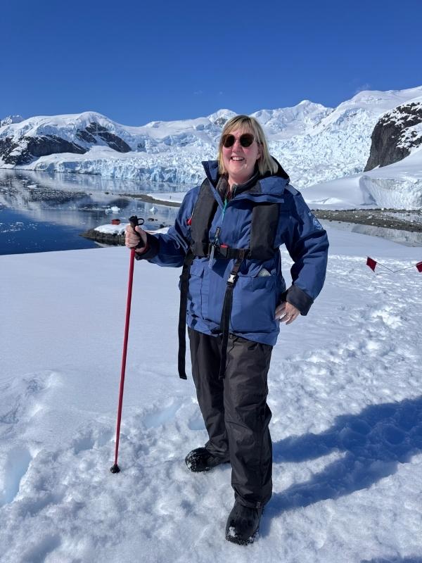 Tracy dressed in waterproof layers holding walking poles on an Antarctic landing